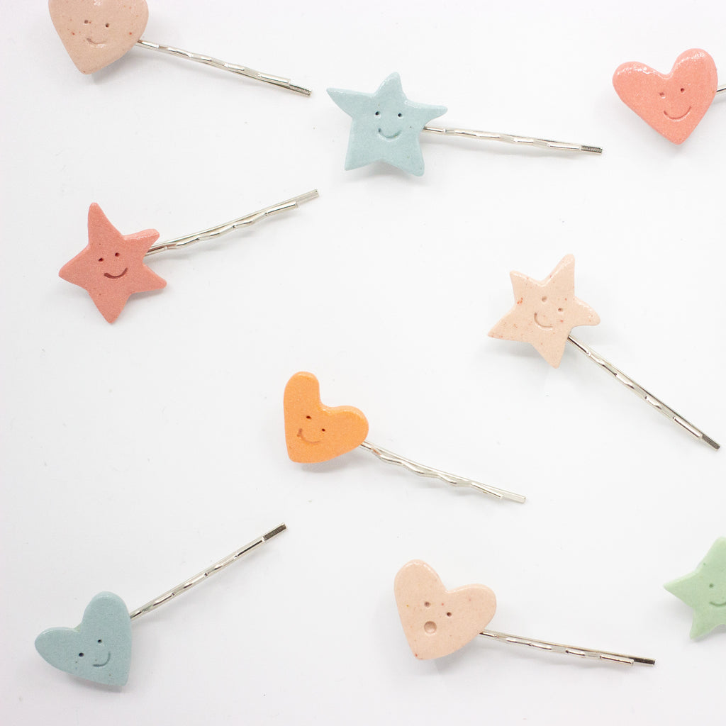 Set of colorful star and heart-shaped hair pins on a white background