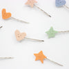 Colorful heart, star, and smiley face hair pins on a white background