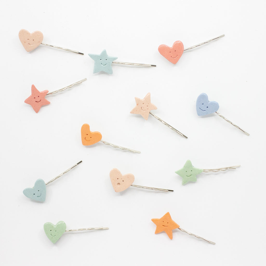 Set of colorful heart and star-shaped hairpins on a white background