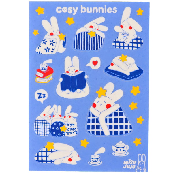 A blue sticker sheet featuring cute cartoon bunnies in cosy scenes, with the text 'cosy bunnies' at the top and the brand name 'Misu Juju' in the lower right corner.