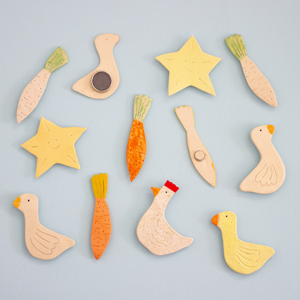 Set of ceramic magnets shaped like animals and vegetables on a light blue background