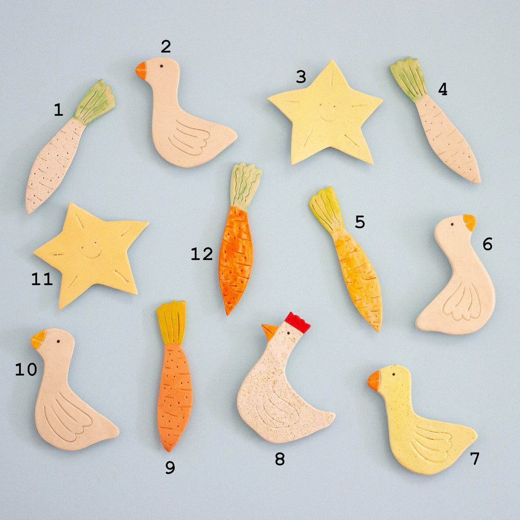 Set of magnetic ceramic figures including birds, carrots, and stars on a light blue background