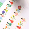 A close-up of decorative paper strips featuring a repeating illustration of girls in colourful dresses walking beside flowers, photographed on a white surface.