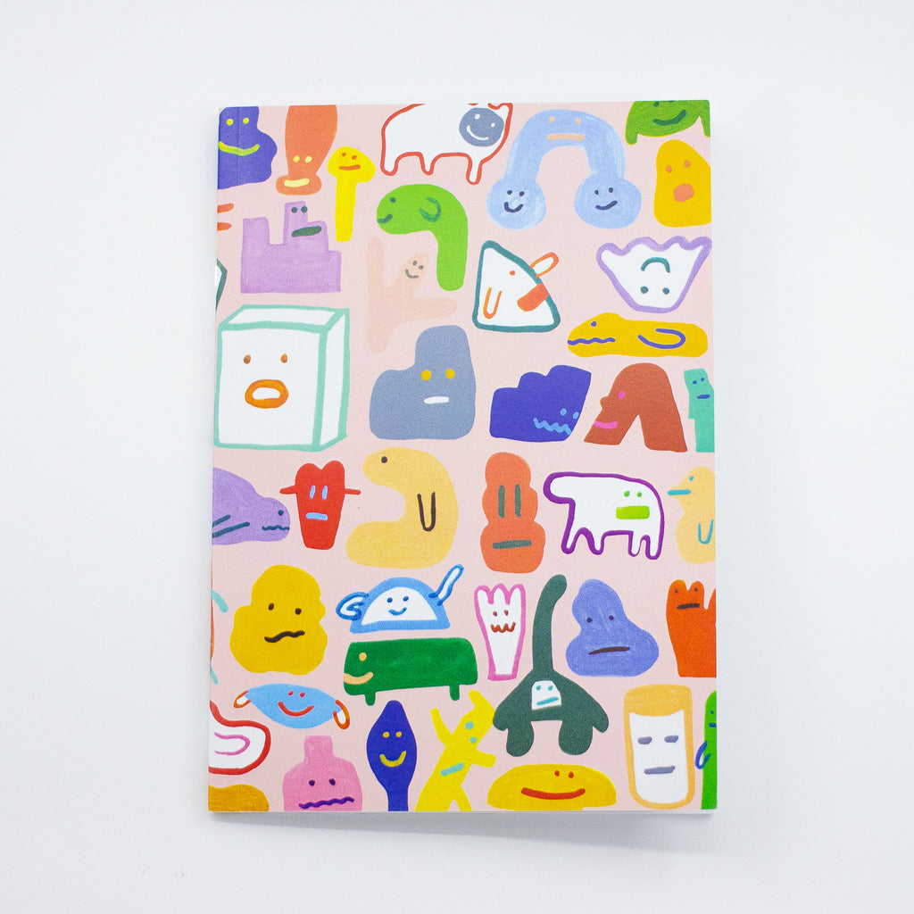 Front cover of the creatres a5 notebook. Pink background with varied characters and monsters from shuh.'s imagation. 