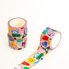Three rolls of washi tape with a colourful cartoon character pattern on a light pink background, arranged on a clean white surface.