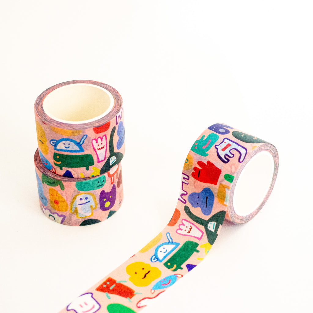Three rolls of washi tape with a colourful cartoon character pattern on a light pink background, arranged on a clean white surface.