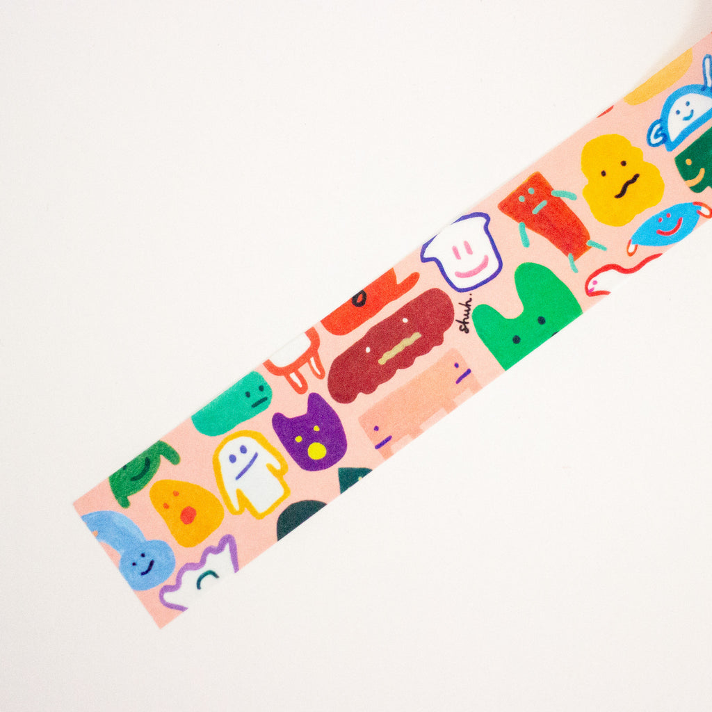 A close-up of a pink patterned strip featuring colourful cartoon characters, shown diagonally on a plain white background.