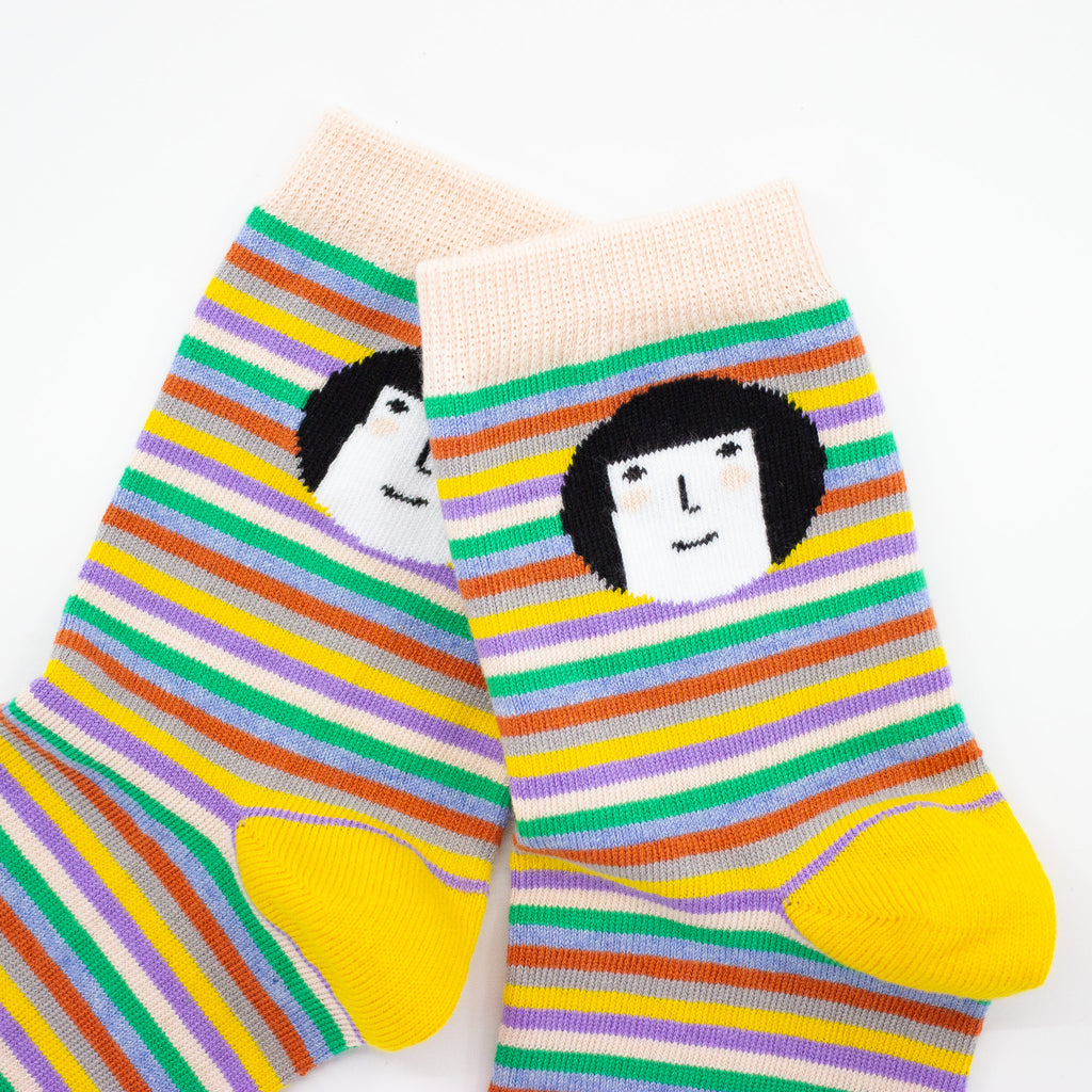 Zoomed side view of the shuh. cutie socks. Focusing on the shuh. girl. Bright striped background with shuh. girl face. Yellow heel. 