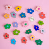 Colourful flower-shaped brooches on a pink background