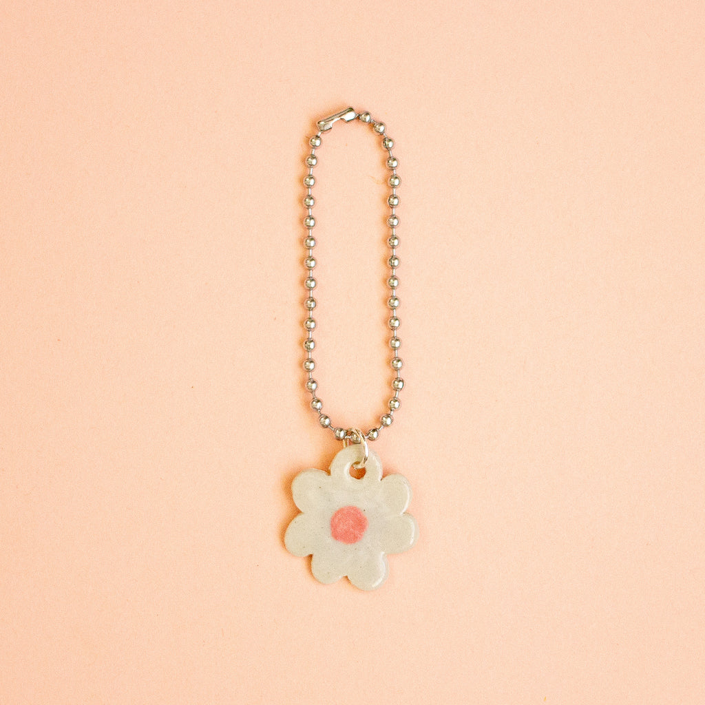 Flower-shaped keychain with a pink center on a peach background