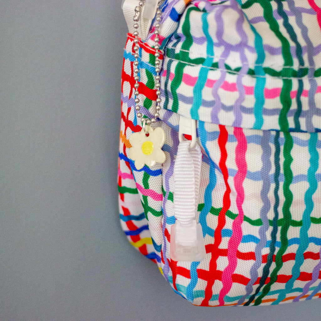 Colourful patterned bag with a keychain and zipper on a grey background