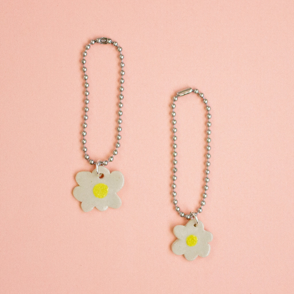 Two flower-shaped keychains on a peach background
