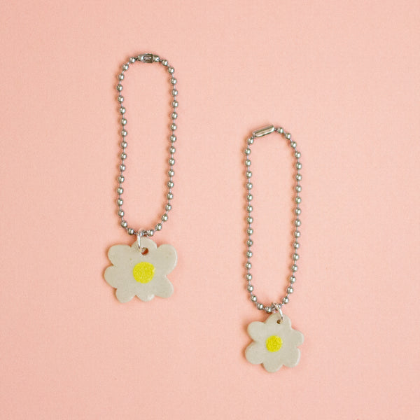 Two flower-shaped keychains on a peach background