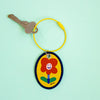 Keychain with a cartoon flower design on a light green background