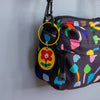 Colourful patterned bag with a keychain featuring a smiling flower design on a plain background