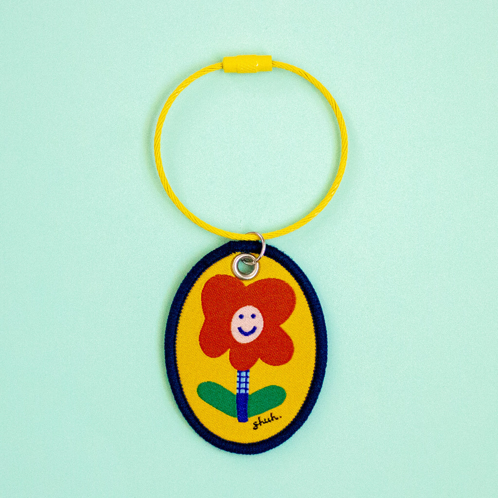Keychain with a red flower design on a light green background