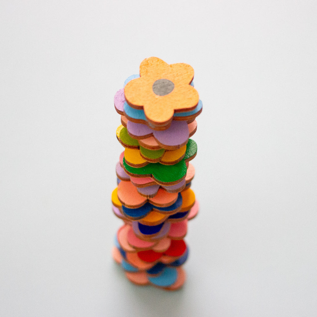 Stack of colourful wooden flowers on a light grey background