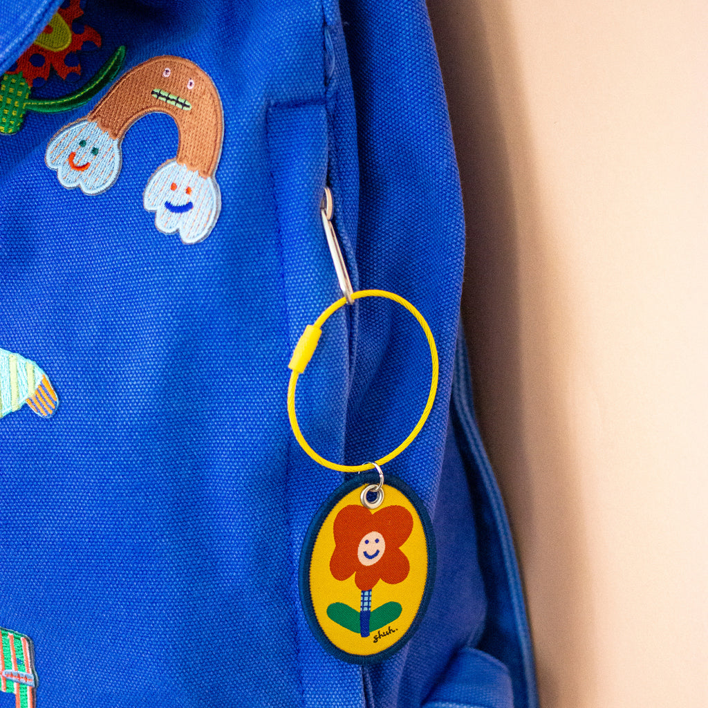 Colourful backpack with a keychain featuring a cartoon face design.