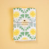 A folded white handkerchief with a green and yellow floral pattern, wrapped in a paper band labeled 'HAIKARA HANDKERCHIEF made in JAPAN', set against a solid pale yellow background.
