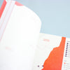 An open book or booklet showing a map of Fukushima Prefecture with red and white graphics, photographed against a light blue background.