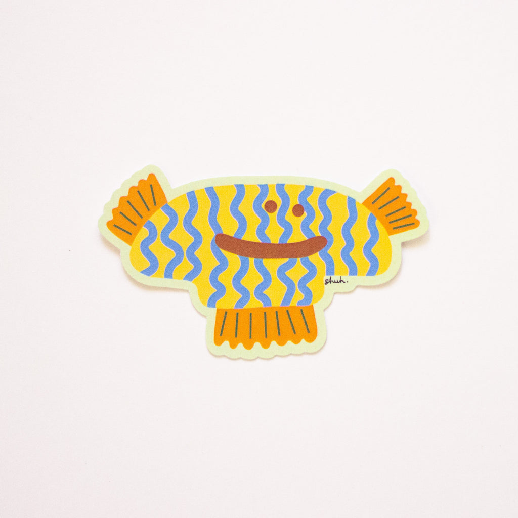 Delia sticker, an underwater style monster with yellow body, blue stripes, and orange fins. 