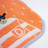 Close-up of a textured orange and white fabric item with a cartoon dog graphic and striped grey trim on a white background.