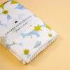 A folded white handkerchief with a light blue and olive green floral pattern, wrapped in a clear paper band that reads 'HAIKARA HANDKERCHIEF made in JAPAN', set against a solid pale yellow background.