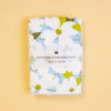 A folded white handkerchief with a light blue and olive green floral print, wrapped in a clear paper band labeled 'HAIKARA HANDKERCHIEF made in JAPAN', set against a solid pale yellow background.