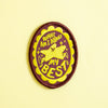 An oval embroidered patch with a dark brown and bright yellow colour scheme, featuring a star character and the text 'WHAT AM I DOING? my BEST'. The patch is displayed on a solid pale yellow background.