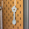 Pastel blue spoon hanging on a pegboard with a brown background