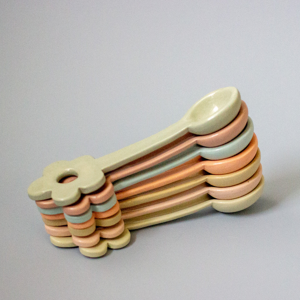 Stack of colorful ceramic spoons on a gray background