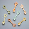 Set of colorful flower-shaped spoons on a gray background