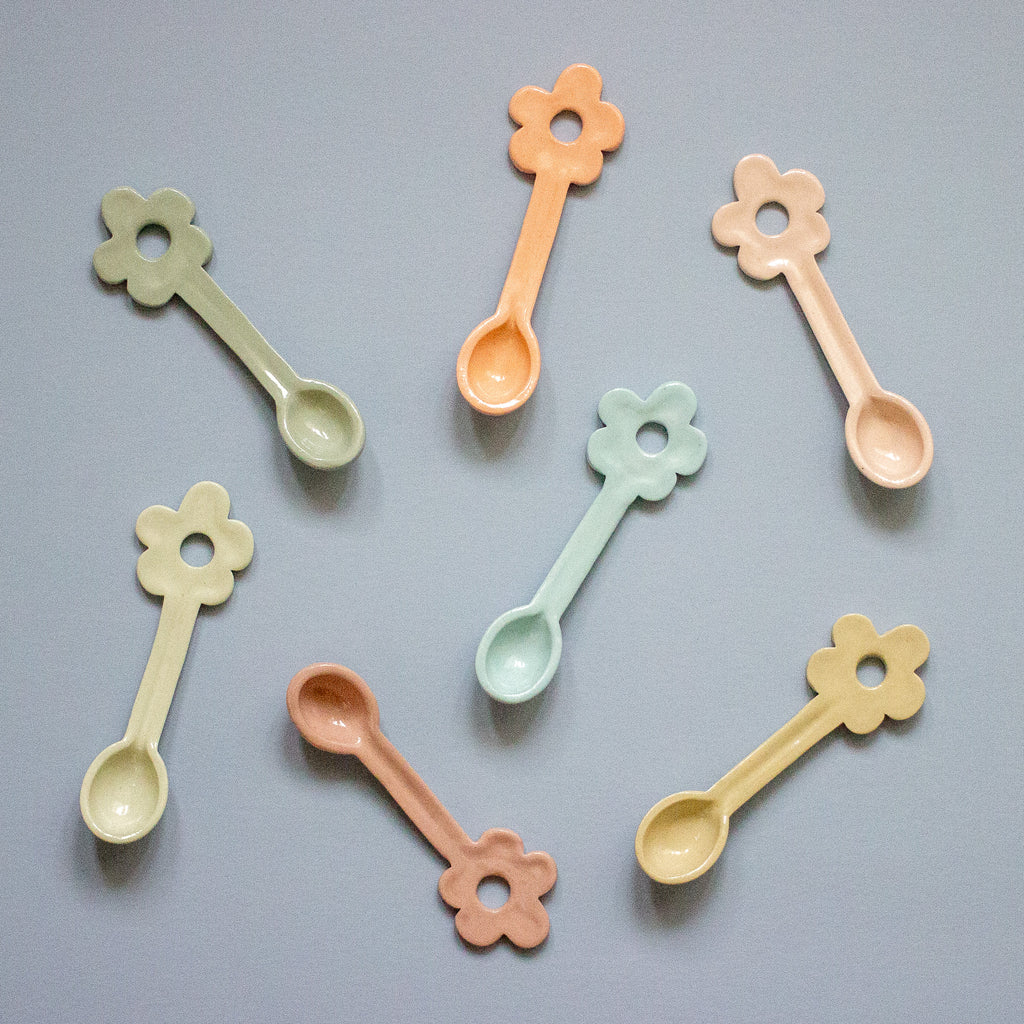 Set of colorful flower-shaped spoons on a gray background