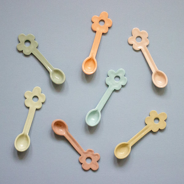 Set of colorful flower-shaped spoons on a gray background