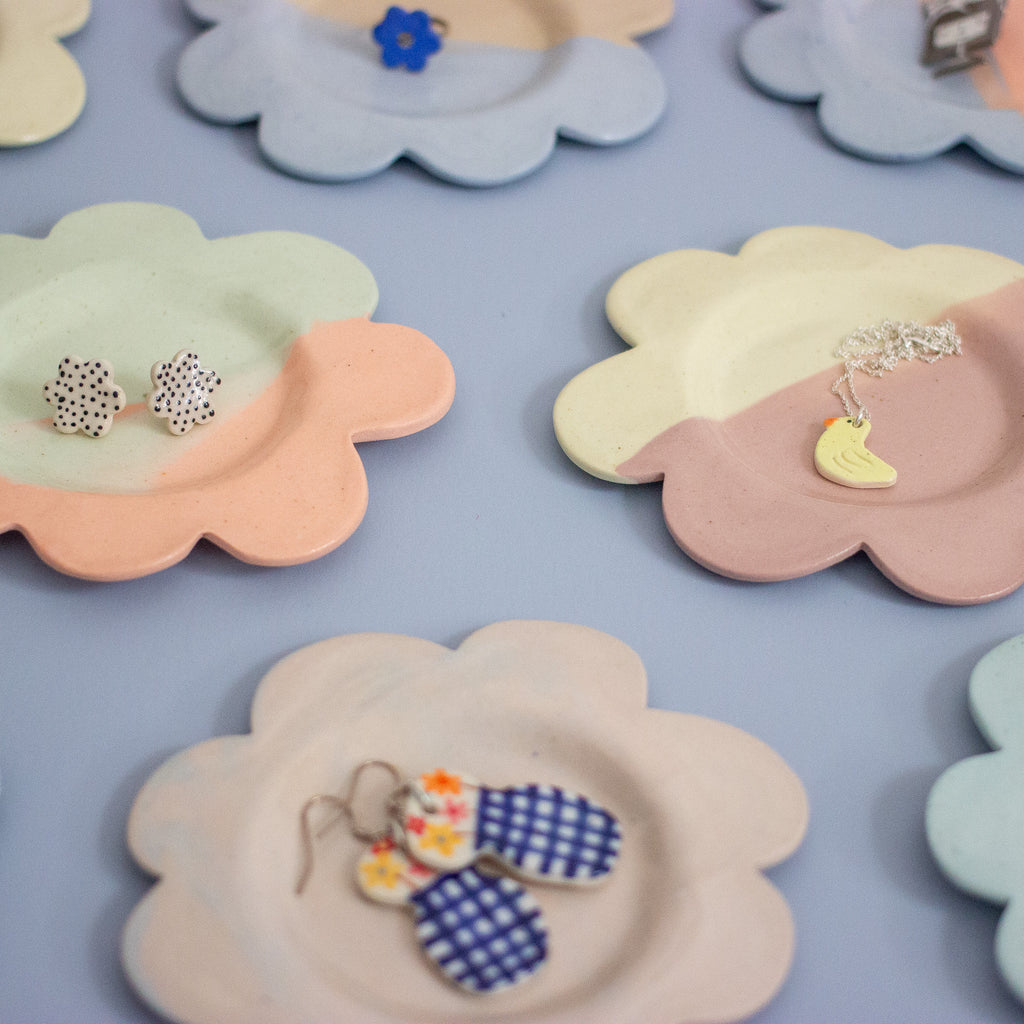 Floral-shaped jewelry holders with earrings on a light blue background