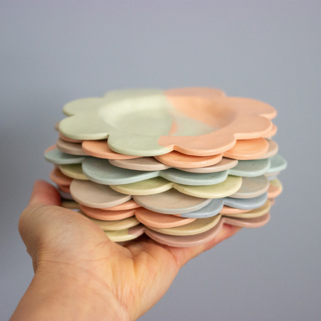 Stack of colorful ceramic plates held in a hand against a gray background