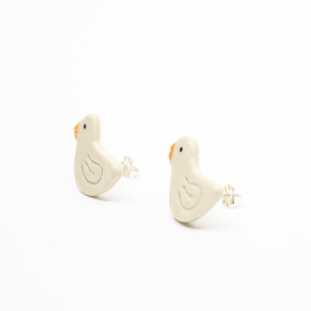 Pair of white bird-shaped earrings with sterling silver studs on a white background