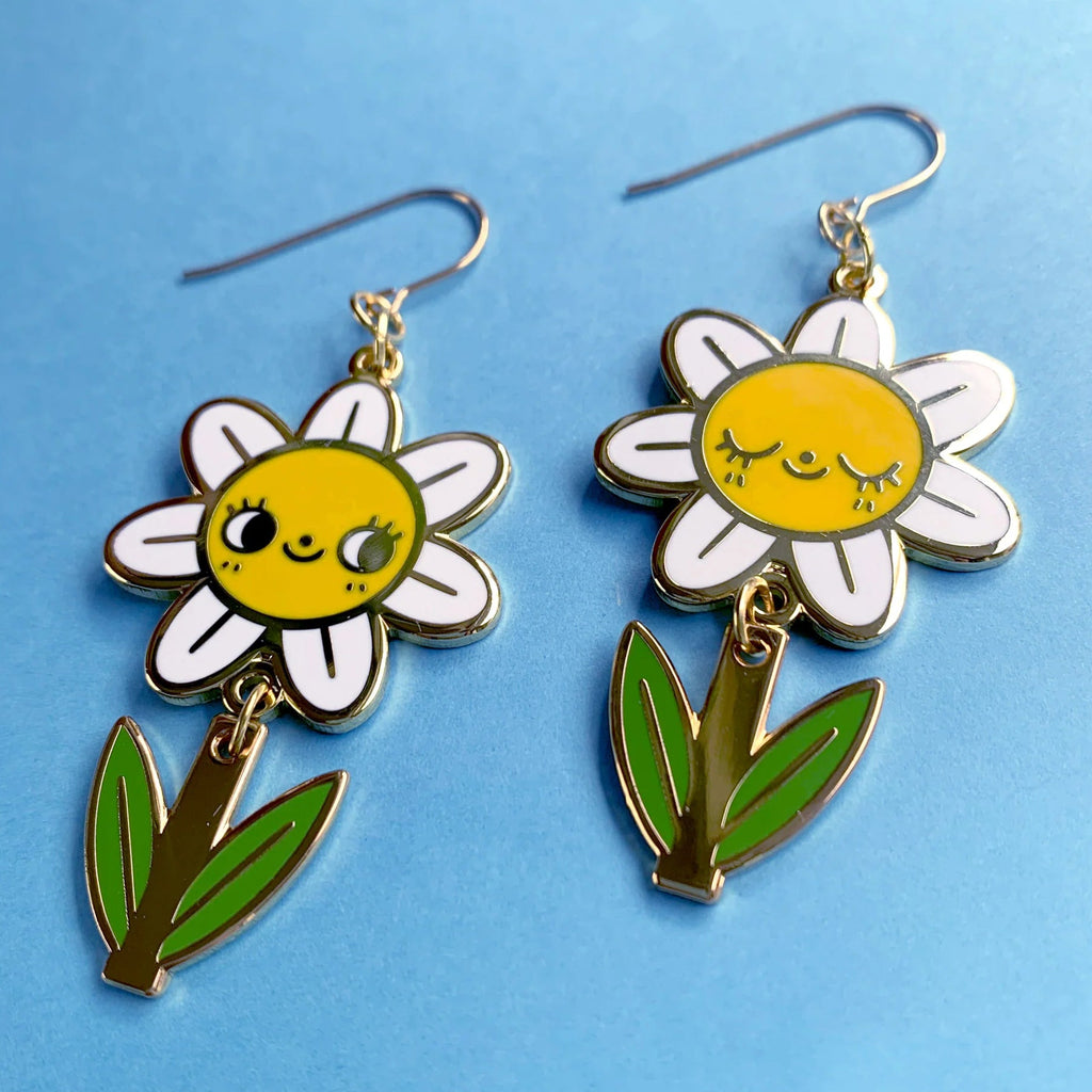 Flower-shaped earrings with smiling faces on a blue background