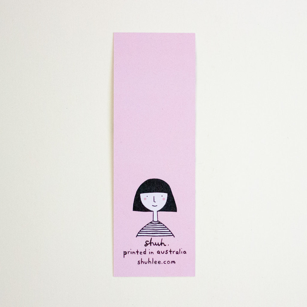 A long, narrow pink bookmark with a simple black line drawing of a person and the text 'shuh. printed in australia shuhlee.com'.