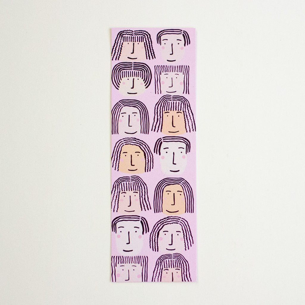 A vertical rectangular bookmark with a repeating pattern of stylised faces, shown flat against a light cream background.