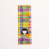 A tall, narrow rectangular bookmark with a colourful abstract plaid pattern and a simple black-and-white illustrated figure near the bottom. The text 'shuh.' and 'printed in australia' are visible near the lower center.