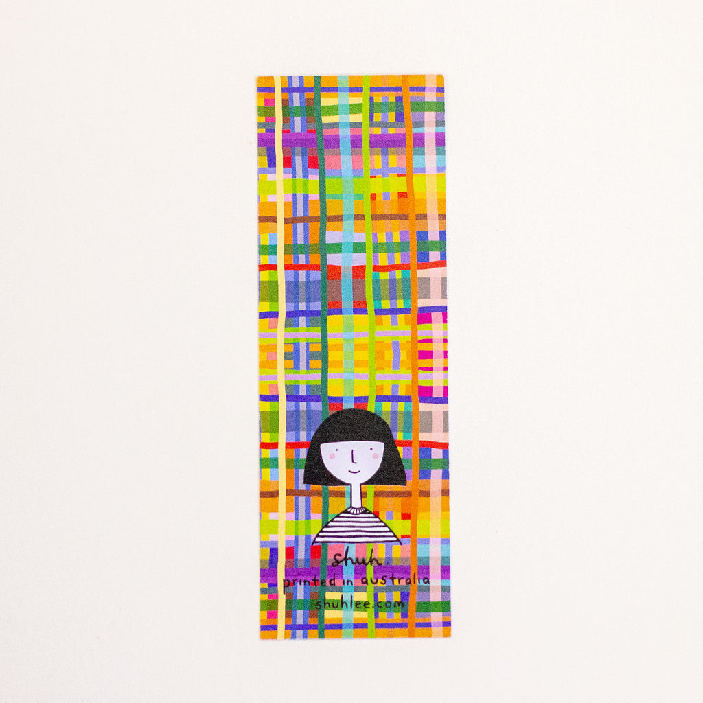 A tall, narrow rectangular bookmark with a colourful abstract plaid pattern and a simple black-and-white illustrated figure near the bottom. The text 'shuh.' and 'printed in australia' are visible near the lower center.