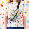 A person carrying the Farm bumbag over their shoulder. Print is multicoloured lines in a grid pattern. 