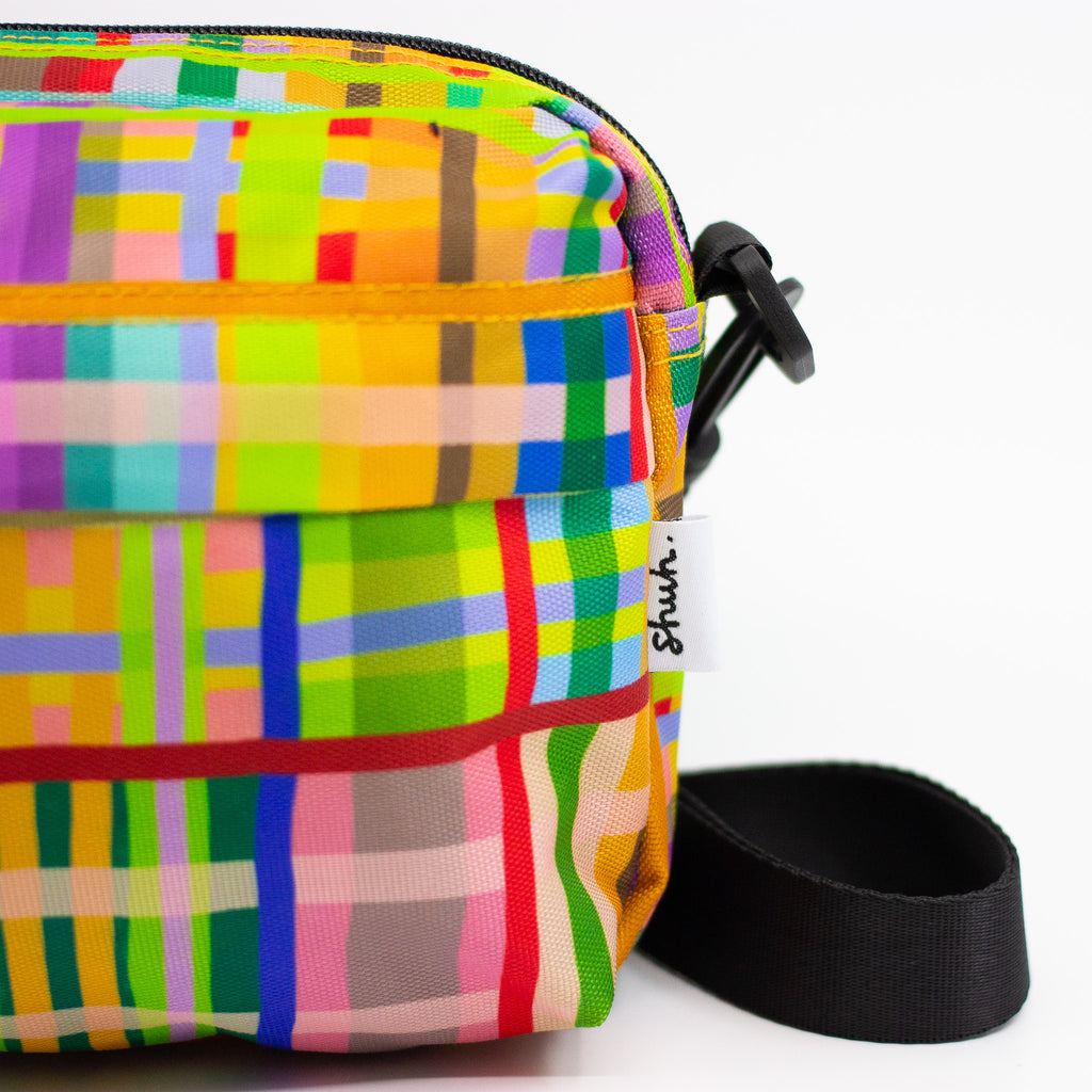 Colorful plaid-patterned bag with a black strap on a white background