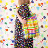 A side view of a model carrying the Farm linen tote back on their shoulder. Print is bright lines in a grid pattern. 