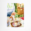 A watercolour art print depicting an orange and white tabby cat sitting on a bed with a breakfast tray in the foreground, set against a bedroom background with a wooden dresser and window.