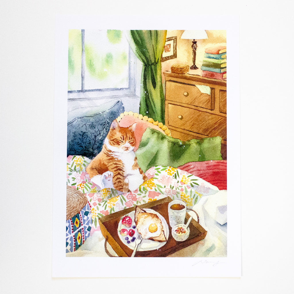 A watercolour art print depicting an orange and white tabby cat sitting on a bed with a breakfast tray in the foreground, set against a bedroom background with a wooden dresser and window.