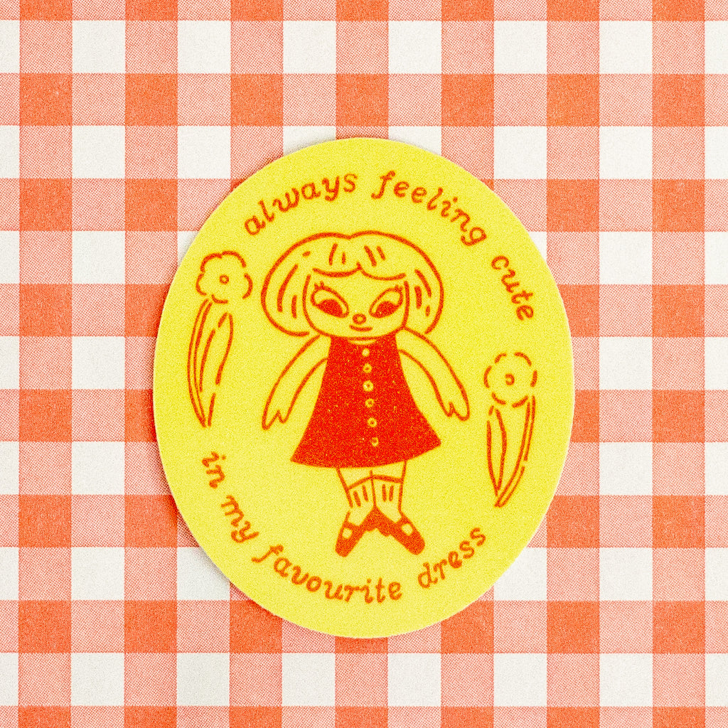 A round yellow sticker with a retro-style illustration of a girl in a red dress and the text 'always feeling cute in my favourite dress', placed on a red and white gingham checkered background.