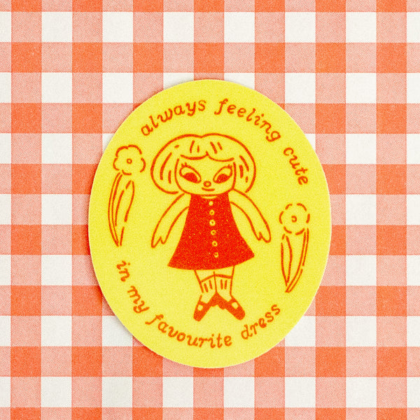 A round yellow sticker with a retro-style illustration of a girl in a red dress and the text 'always feeling cute in my favourite dress', placed on a red and white gingham checkered background.