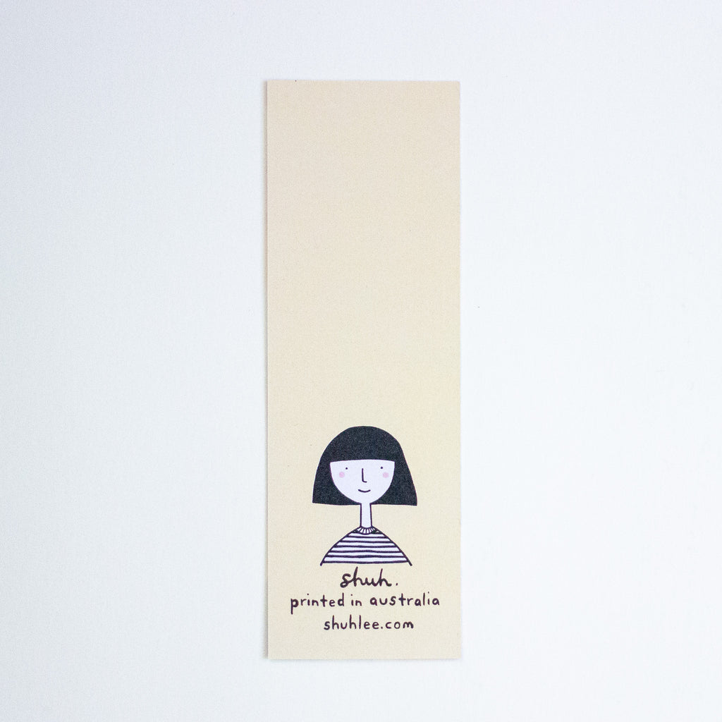 A tall, narrow cream-coloured paper bookmark featuring a minimalist black line drawing of a girl with a bob haircut and the text 'shuh., printed in australia shuhlee.com' at the bottom, shown against a plain white background.